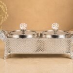Silver ornamental double-lidded caddy with crystal knobs on a beige countertop