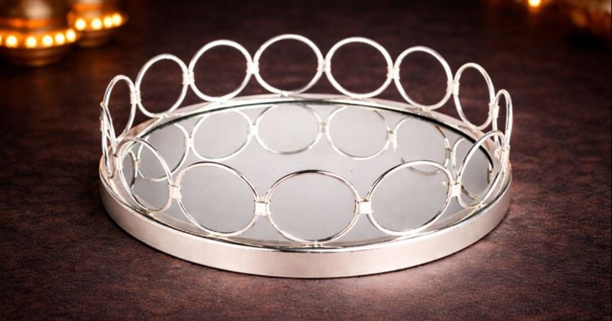 Round silver mirror tray with a border of circular metal rings around the edge.