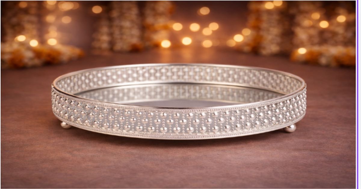 Silver studded bangle bracelet on a brown surface with warm bokeh lights in the background, reflecting softly in its mirror-like interior.