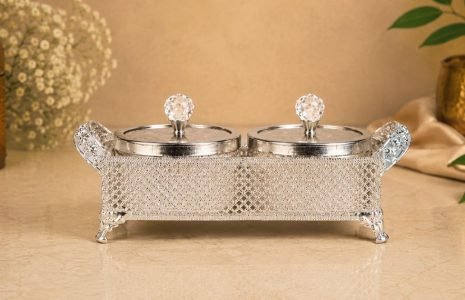 Silver ornamental double-lidded caddy with crystal knobs on a beige countertop