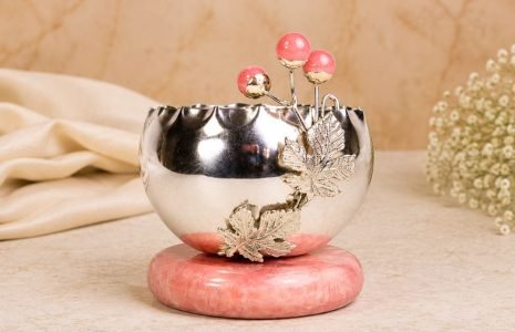Polished silver decorative bowl with a pink stone base, carved maple leaves and pink-tipped orb accents, set on a pink stand.